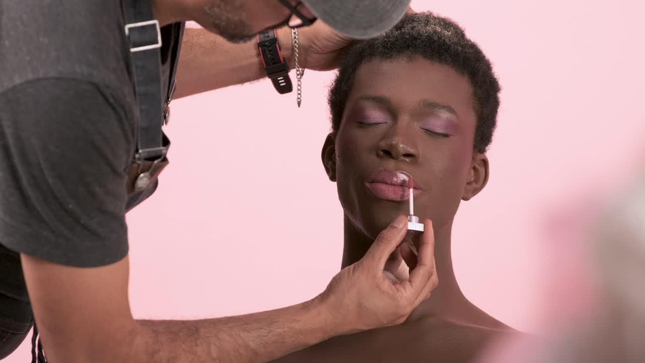 Crop visagiste doing professional makeup on transgender person