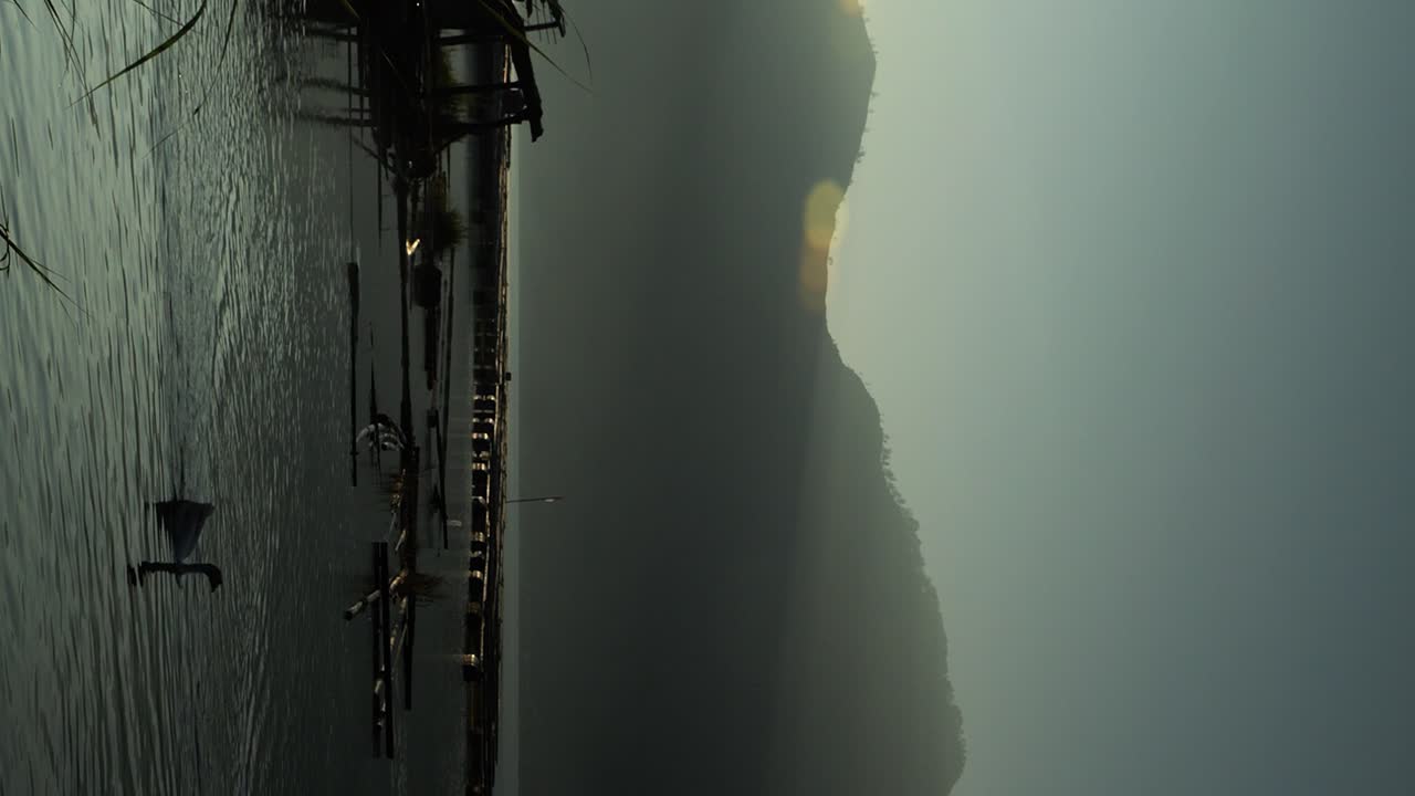 toma vertical de la imagen ascendente del lago volcánico batur con vista a la montaña batur y el lago tranquilo con patos nadando en una hermosa mañana durante la hora dorada