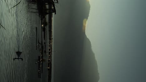 vertical shot of rising image of volcanic lake batur with view of mountain batur and the calm lake with swimming ducks on a beautiful morning during golden hour