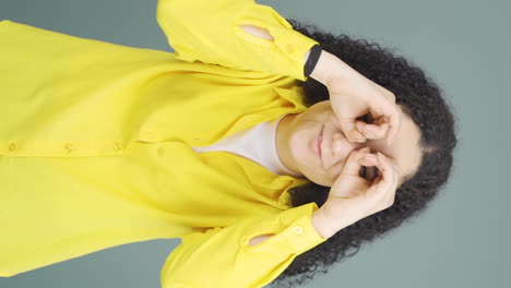 vertical video of young woman with binoculars looking away.