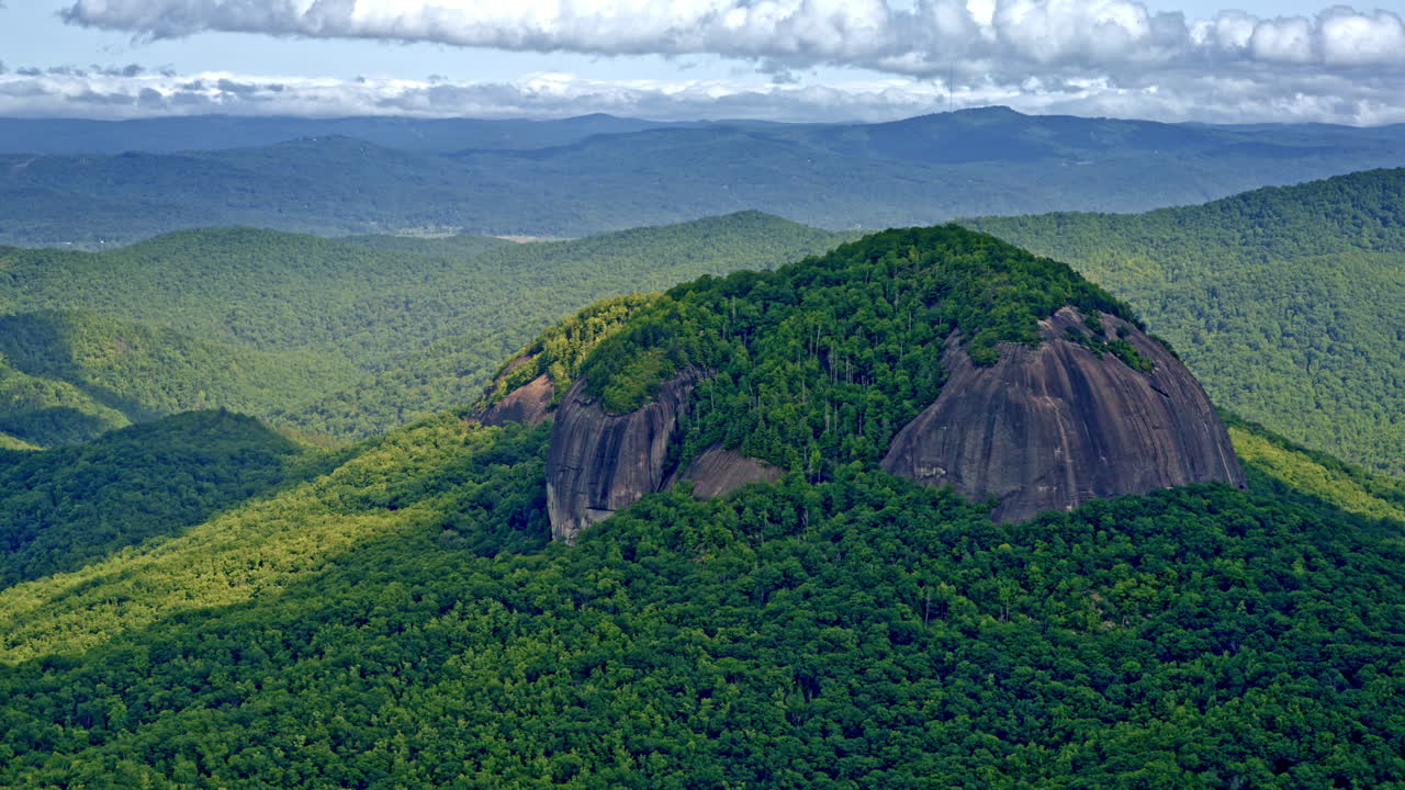 Sweeping drone shot of a towering, stand-alone mountain detached from the main range