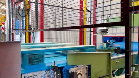 proceso automático en tiempo real de pintura de europallets azules mientras se mueven en una cinta mecánica antes de ser impresos y apilados