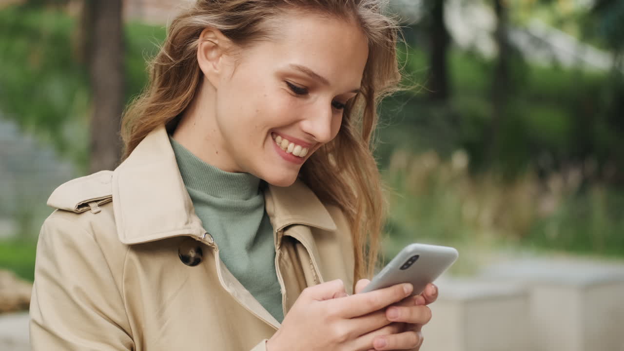 Caucasian female student using smartphone outdoors.
