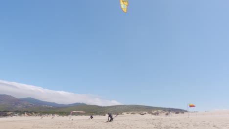 A-Windsurfer-Adjusting-his-Windsail-and-Walking-towards-the-Water-at-Praia-do-Guincho,-Portugal