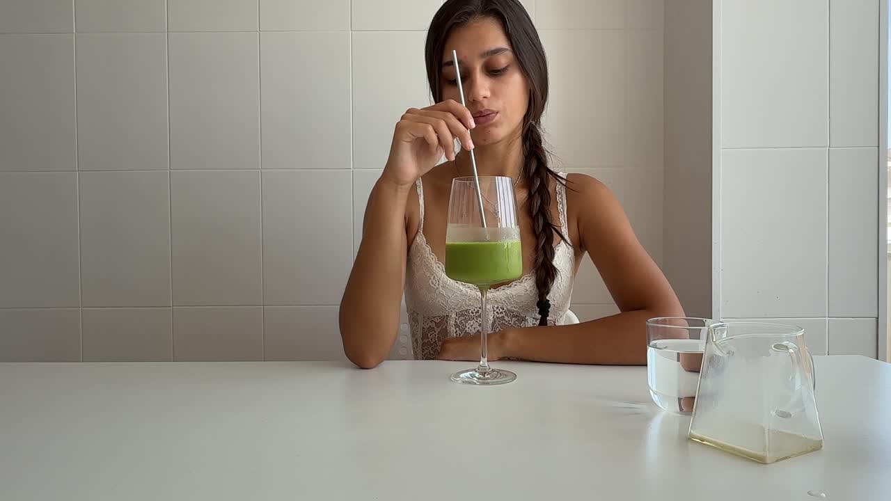 Giovane donna che mescola e beve un sano frullato verde.