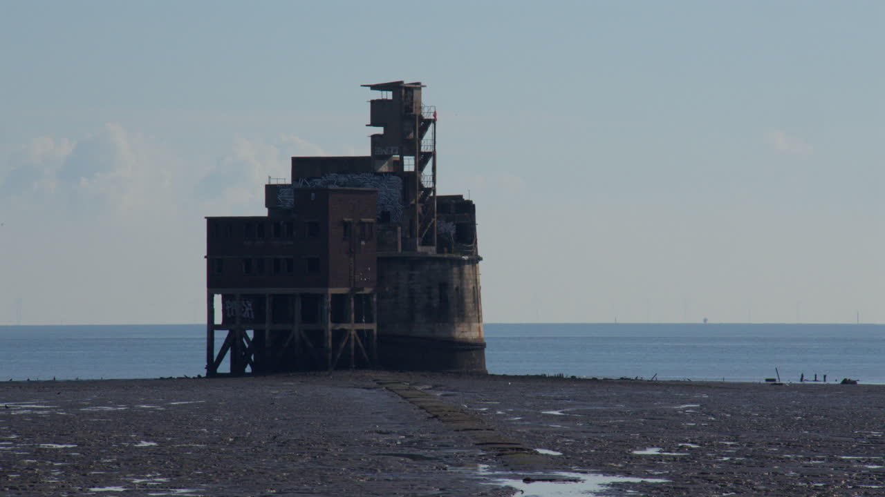 Groot overzicht van de graanbatterijtoren bij eb, links in beeld.