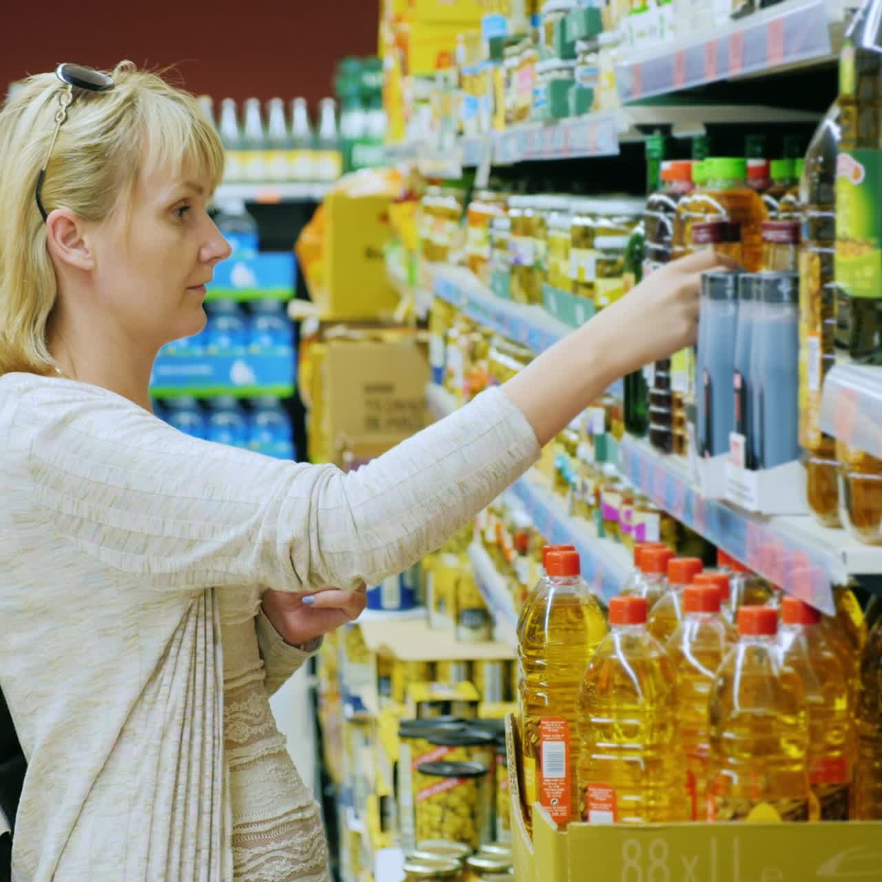 el comprador elige aceite de oliva en el supermercado