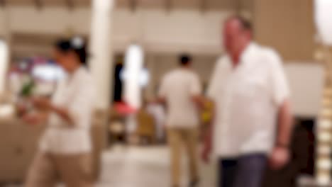 People engage in casual conversation in a warmly lit hotel lobby, creating a relaxed and social atmosphere
