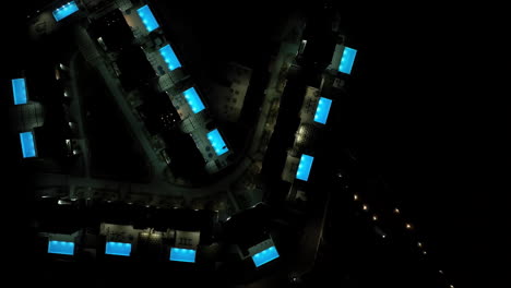 birds eye drone shot over night lit pools and villas at a resort in greece