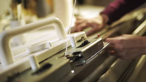 Woman-knitter-hand-working-on-weaving-machine.-Knitting-machine-production