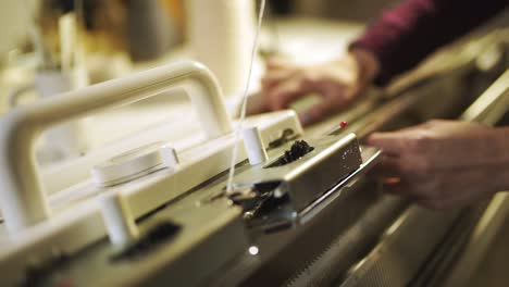 Woman knitter hand working on weaving machine. Knitting machine production