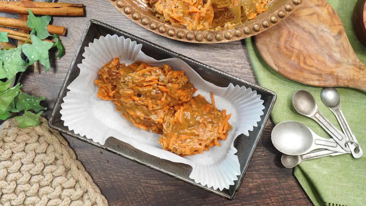 Baking a carrot cake loaf with cream cheese icing and topped with roasted salted pecans. Making a Autumn dessert with carrots, flour, sugar, nuts and frosting. Adding batter to a baking loaf pan.