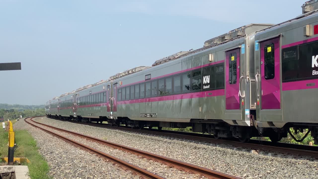Passenger train passes through rural rice fields, curved double track