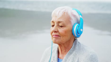 mujer mayor escuchando música en los auriculares en la playa