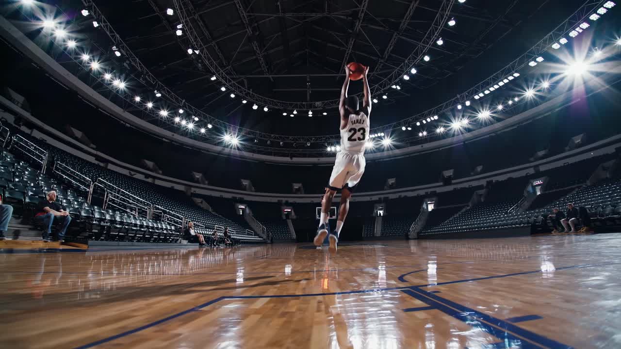 Wide-angle shot of a basketball player dribbling on a court in a large arena