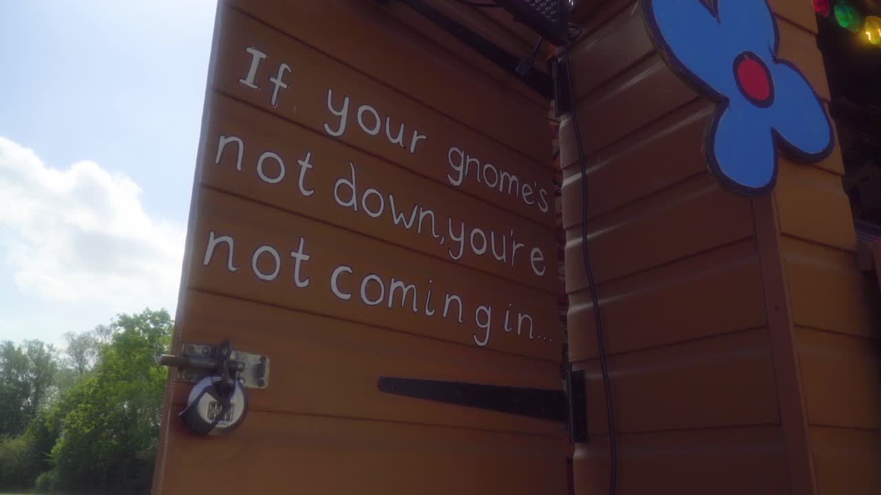 brown vintage wooden door with a lock and funny message crafted blue flower hanging on the shed partly cloudy sky and nature