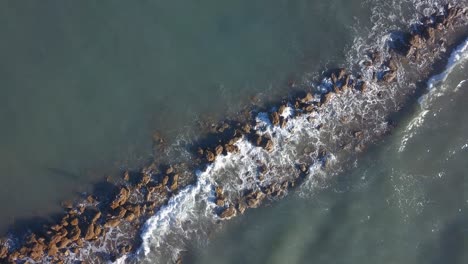 Foamy-Waves-Breaking-On-Rocks---Espigon-de-Sancti-Petri-In-Chiclana-de-la-Frontera,-Cadiz,-Spain---aerial-top-down