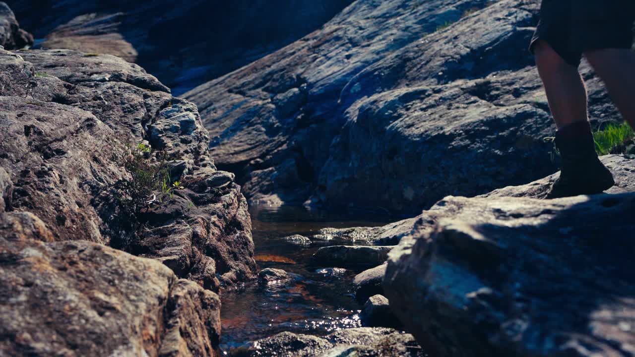 사람 은 바위 를 가로질러 흐르는 하천 에서 고 물 을 마신다