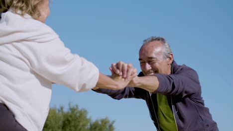 Happy-man-and-woman-holding-hands-and-lunging-forward-outdoor