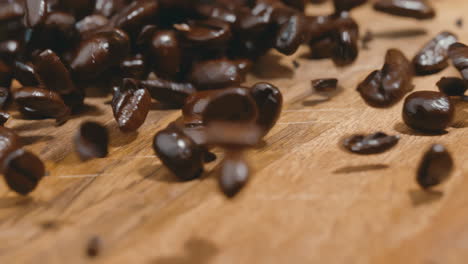 Fresh-coffee-beans-spilling-onto-wood-table-in-extreme-slow-motion