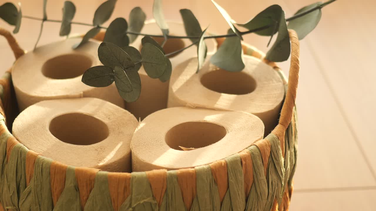Toilet paper rolls in a basket with eucalyptus