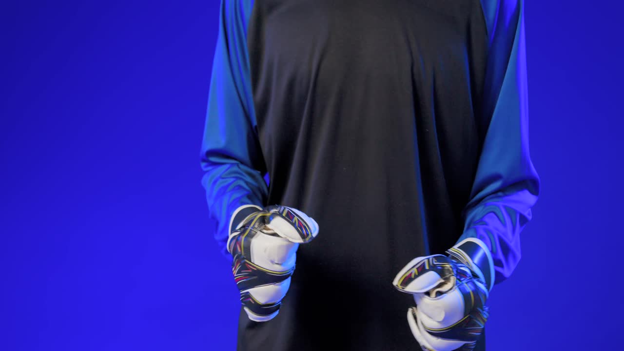 Video verticale: Uomo che indossa i guanti, allaccia le cinghie, flette le mani preparandosi ad afferrare in un set blu.