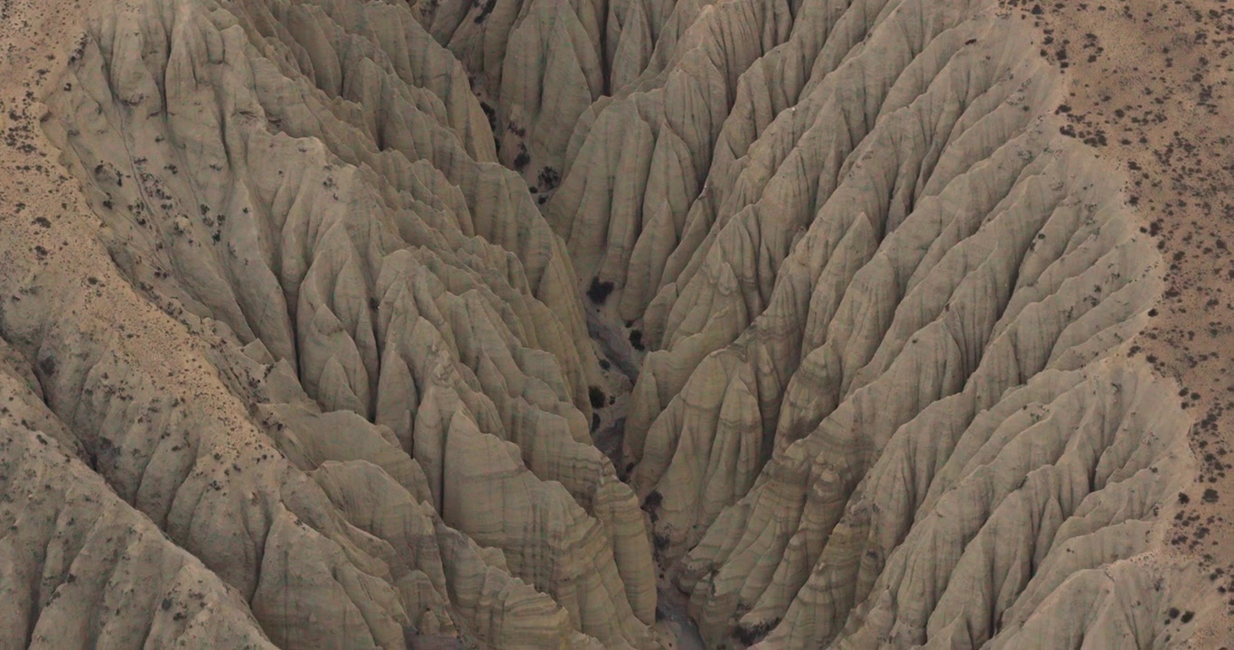 Drone scivola dolcemente su un incredibile canyon montano di argilla profondamente solcato, rivelando modelli di erosione naturale e formazione di colline nelle valli del Mustang, Nepal
