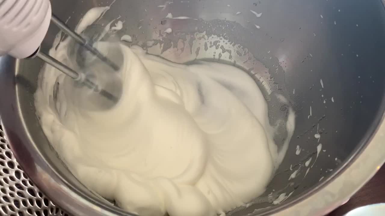 An ultra power hand mixer whipping egg whites into a thick and foamy consistency.