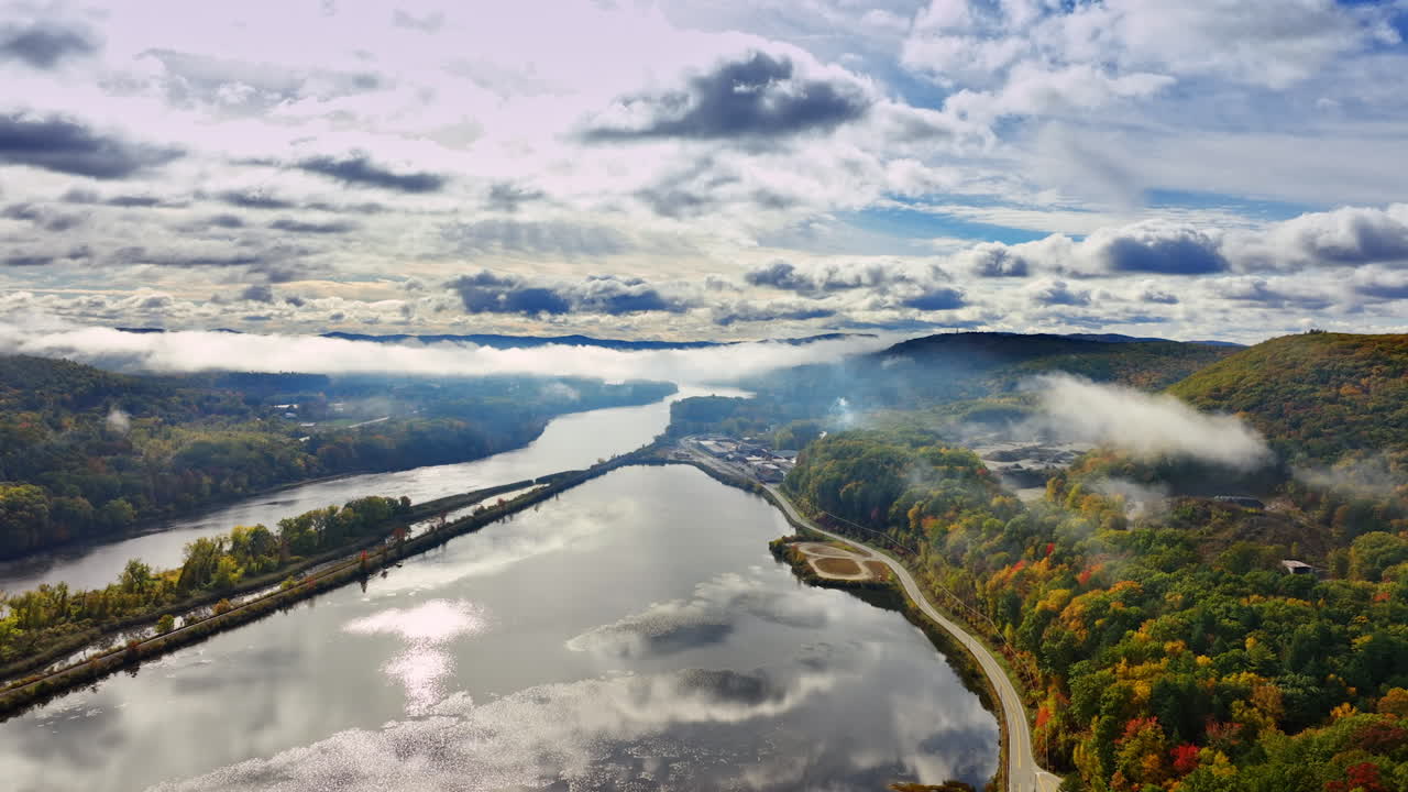 Lake Champlain in Vermont, New England, USA reflecting the overcast sky. Lush woods changing colors in autumn surround the waterscape. Aerial view.