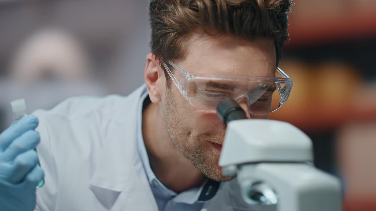 científico emocionado trabajando en el microscopio regocijándose de la investigación en el laboratorio de cerca.