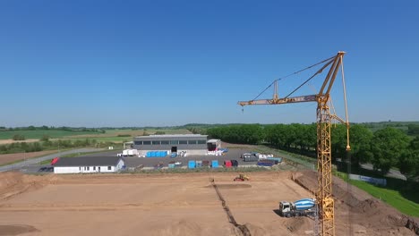 Eine-Drohne-Fliegt-über-Eine-Großbaustelle,-Auf-Der-Eine-Riesige-Produktionshalle-Gebaut-Wird