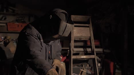 el hombre recoge el portaelectrodos preparándose para comenzar la soldadura por arco de metal blindado de acero inoxidable