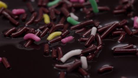 Close-up of sugared colored sprinkles falling on a chocolate candy