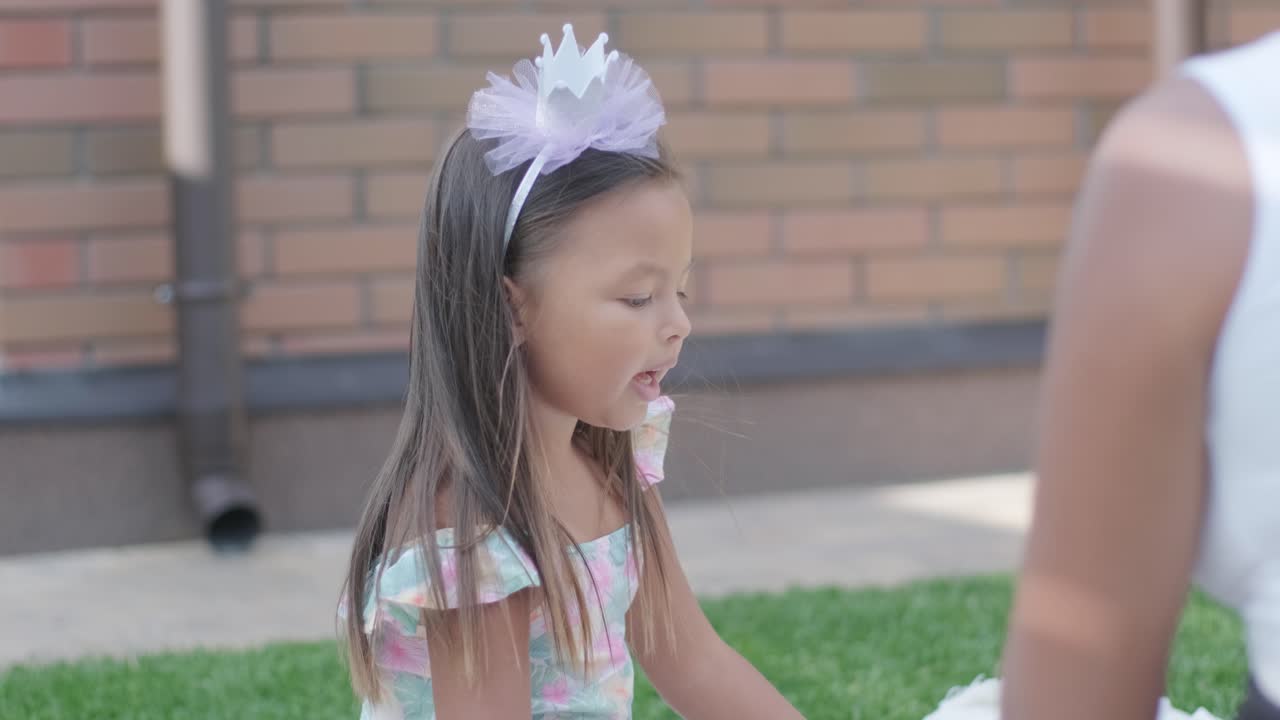 엄마와 어린 딸이 뒷마당에서 담요 위에 앉아 함께 그림을 그리고 있습니다. 야외 장면은 평화로운 가족 순간을 포착하여 창의성과 유대를 촉진합니다.