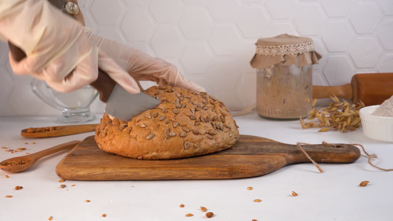 The chef cuts homemade bread. Sourdough in a jar on the background. Close-up