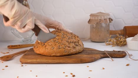 the chef cuts homemade bread. sourdough in a jar on the background. close-up