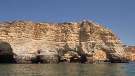 A-group-of-canoes-passing-through-sea-cave-arches-in-the-Algarve,-Portugal