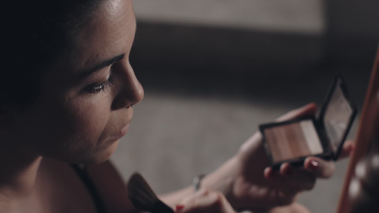 Close up of young woman applying make up with a brush