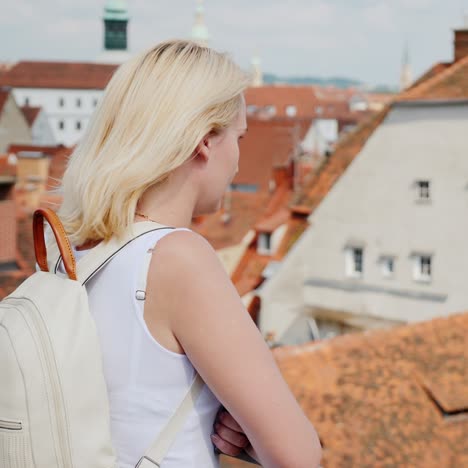 a young woman tourist is admiring the old european city from a height