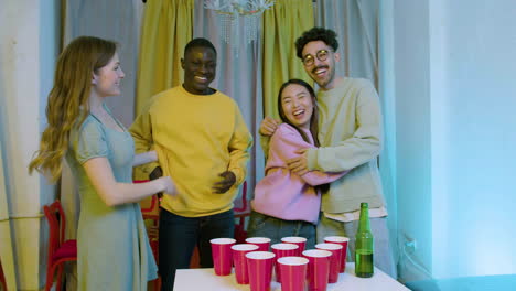 felices jóvenes amigos multiétnicos jugando al pong de cerveza en casa