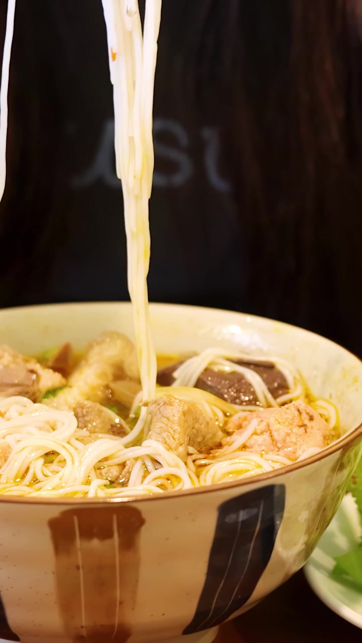 Sollevare noodles fumanti da una ciotola di Bun Bo Hue