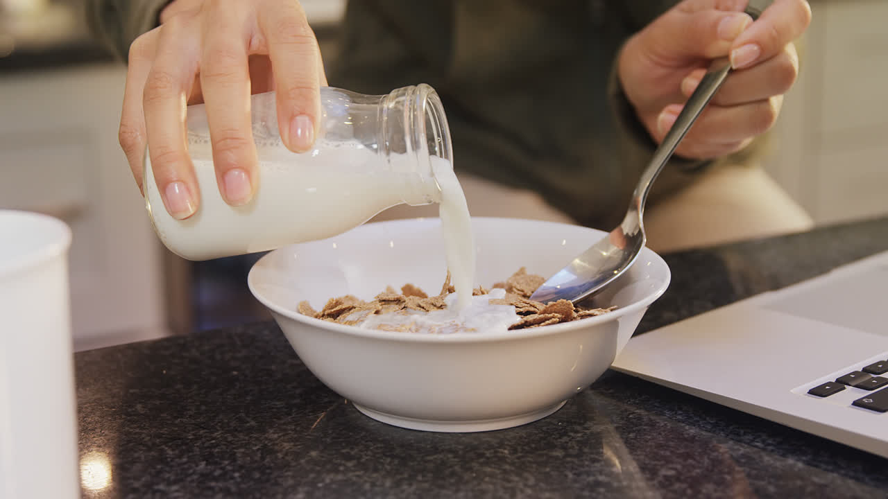 mujer en la cocina vertiendo leche en copos de maíz 4k 4k