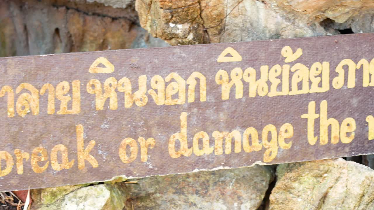 надпись в пещере лава, канчанабури, предупреждает посетителей не повреждать скалы. видео показывает текст надписи при естественном освещении