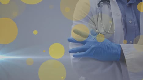 Yellow-spots-floating-against-mid-section-of-a-doctor-wearing-surgical-gloves