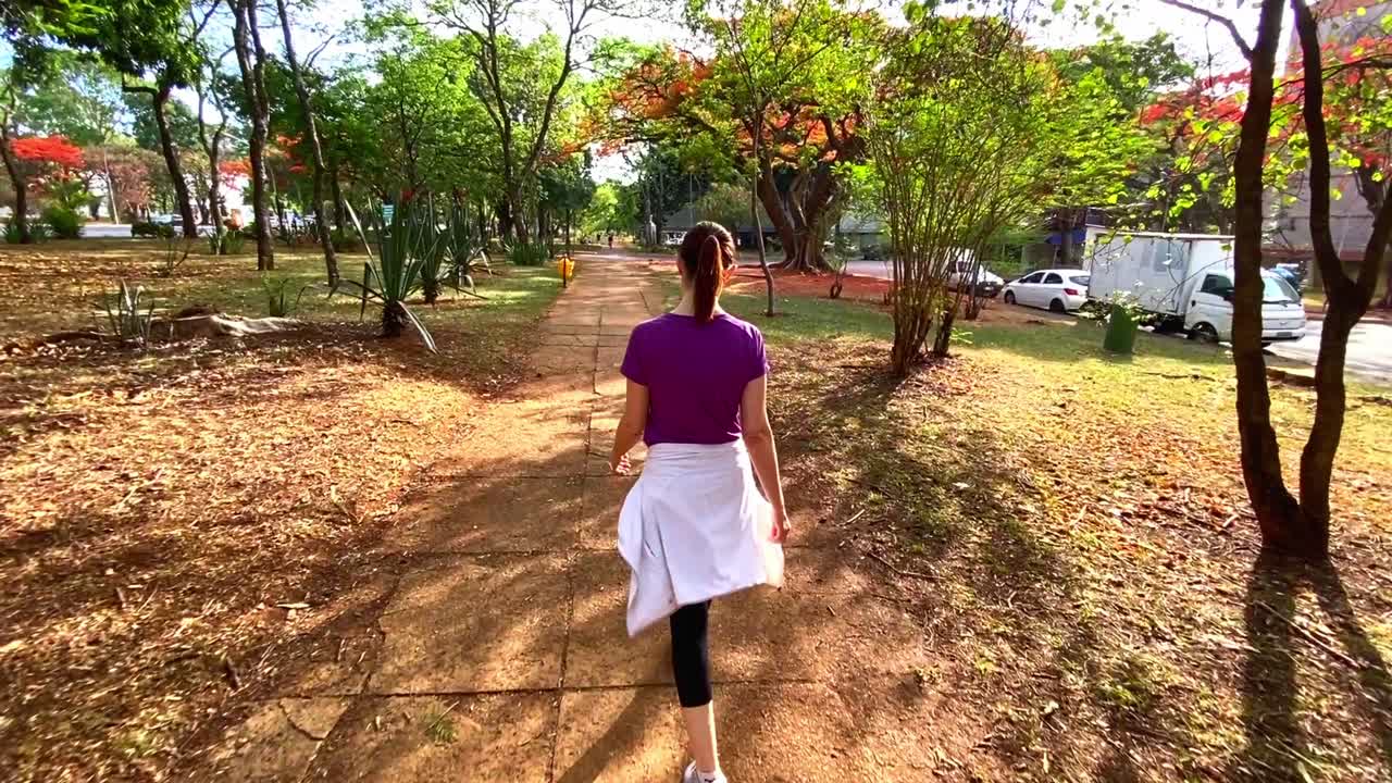 운동복을 입은 날씬한 여성이 가을에 도시 공원을 산책합니다.