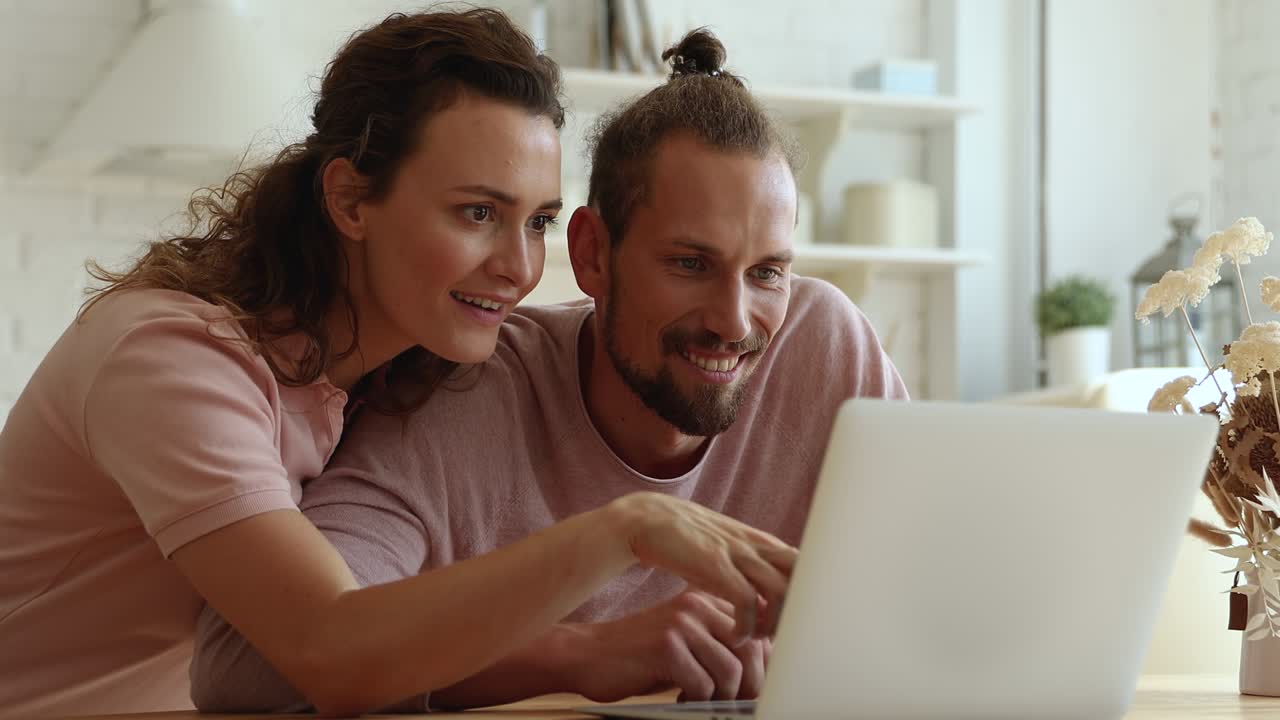 una pareja pasa el fin de semana en casa en la cocina usando una computadora portátil.