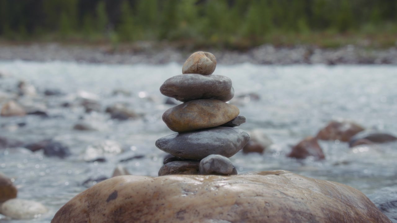 Stack of balanced stones against the flowing mountain river background