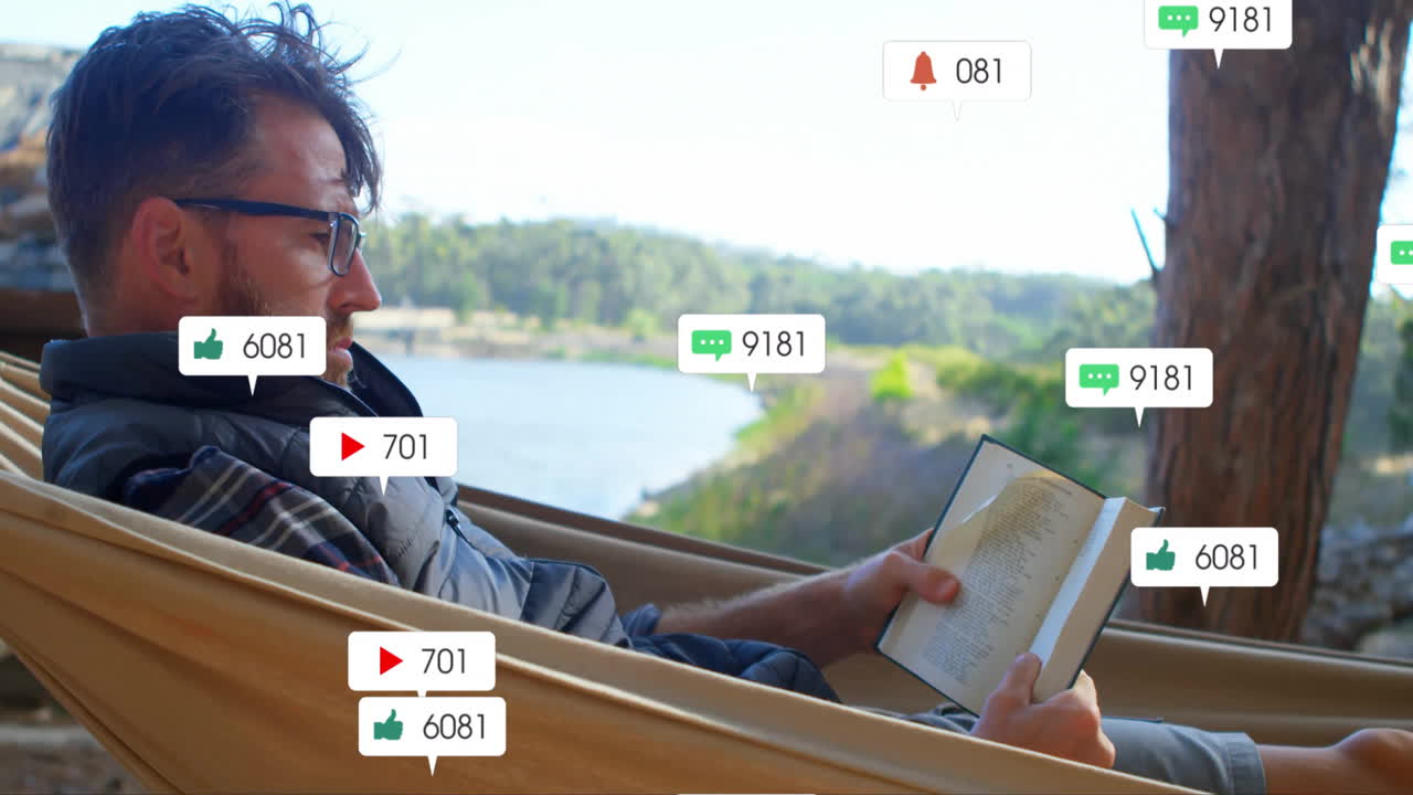 Man reclining in lakeside hammock reading book, displaying animated social media marketing icons