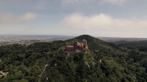 pena palace against the lush forest and cloudy sky, sintra natural park, portugal