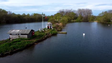 Aerial-drone-view-of-a-shelter-on-a-small-island-surrounded-by-bay-water-with-green-forestry-in-the-background